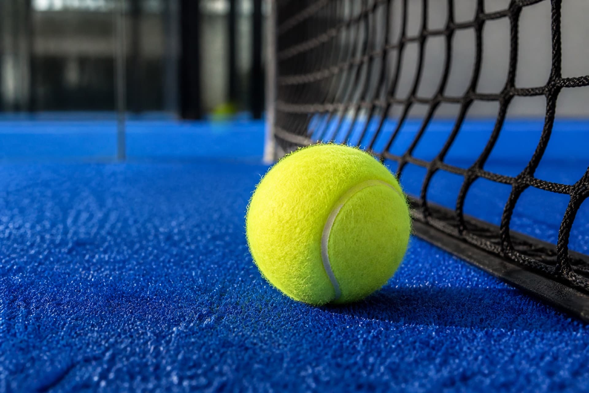 Padelball am Netz auf blauem Court